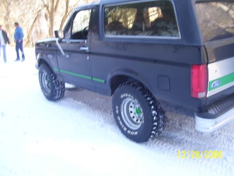 1993 Ford Bronco - 1993 Ford Bronco parked in the snow with two people standing nearby.
