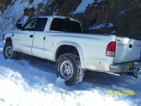 1993 Ford Bronco - White Dodge pickup truck with off-road tires driving in snow.