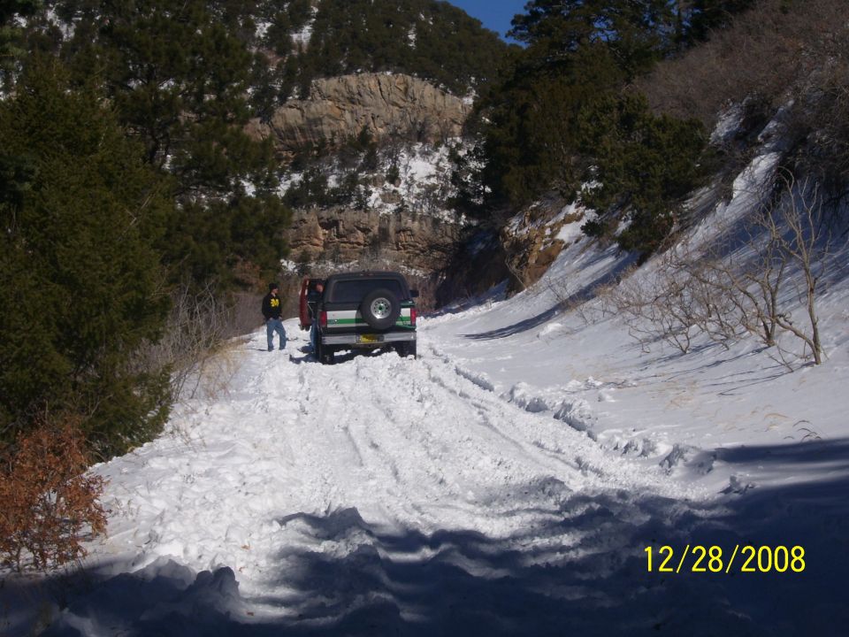 Rear view of a 1993 Ford Bronco on a snowy road with a person standing nearby