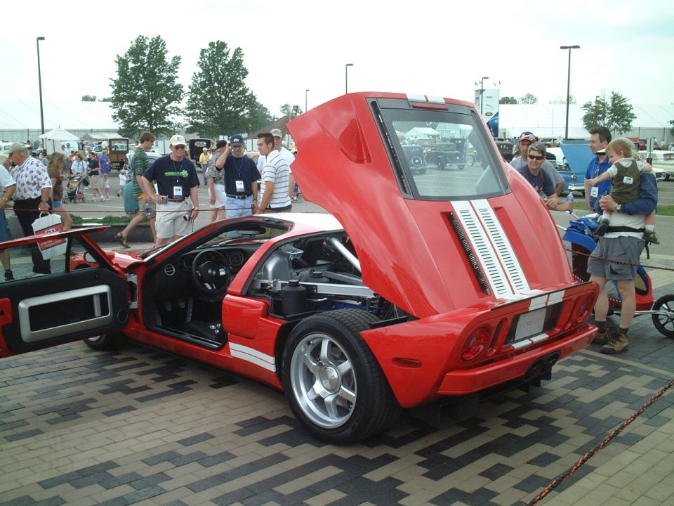 Red Ford GT with white stripes, rear clamshell and door open at a car show