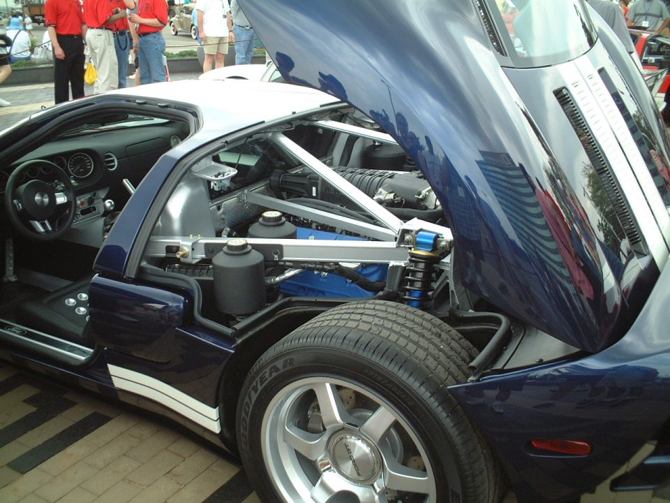 Blue Ford GT with rear clamshell open showing mid engine at a car show