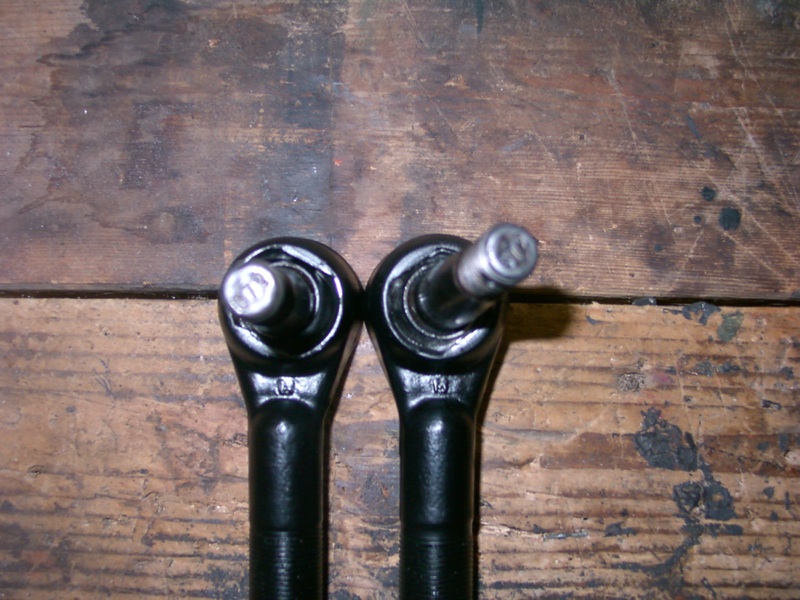 Two black tie rod ends on a wooden surface