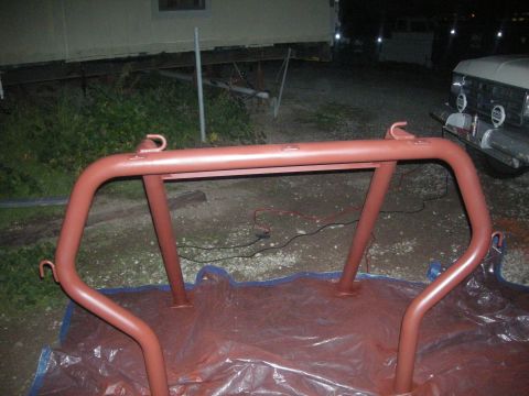 1991 Ford Bronco - Roll cage section painted red and drying on a tarp outdoors.