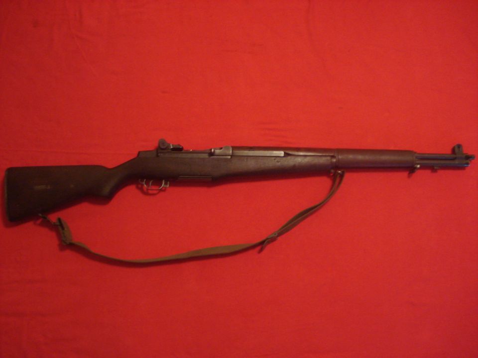 M1 Garand rifle with wooden stock and sling on a red background