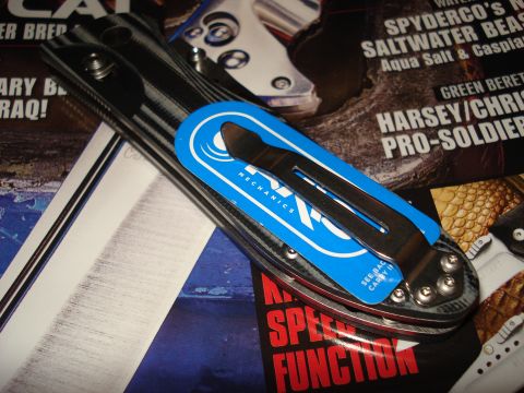 2000 Ford Crown Victoria - A knife with a blue packaging insert that reads 'Mechanics' is shown resting on magazine pages.