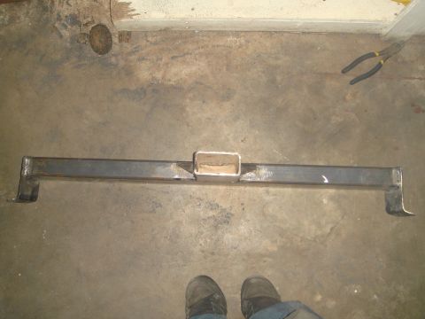 1992 Ford Bronco - A fabricated steel receiver hitch is laid out on a concrete floor. The hitch has a central receiver tube and angled mounting brackets on ea…