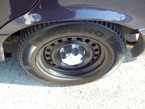 1999 Mercury Grand Marquis - A close-up view of the driver's side rear wheel and fender of a dark purple vehicle. The tire is a Kumho brand, and the wheel appears to be…
