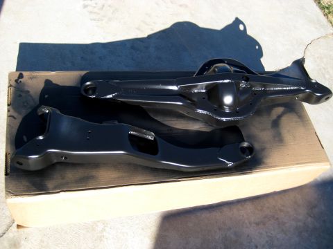 1996 Ford Bronco - Two black painted rear axle components, likely from a 1996 Ford Bronco, are resting on a cardboard box outdoors. The components appear to b…