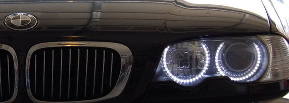 Black BMW sedan front end with chrome grille and LED angel eye headlights.