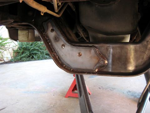 1996 Ford Bronco - A close-up view of a welded reinforcement plate on the frame of a vehicle, likely a 1996 Ford Bronco, supported by jack stands.