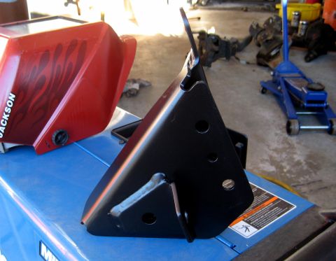 1996 Ford Bronco - A black metal bracket with multiple holes is shown in the foreground, resting on a blue surface. To the left, a red fuel tank with black fl…
