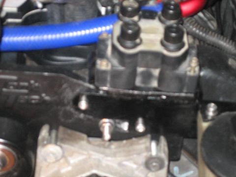 1996 Ford Thunderbird - A close-up view of a vehicle's engine bay shows a black ignition coil pack with four black spark plug wires connected. A blue hose is visib…