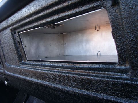 1978 Ford Bronco - A custom aluminum storage compartment has been installed into the textured black dashboard of a vehicle. The compartment is open, revealing…