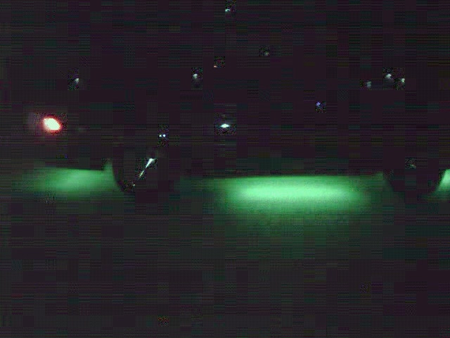 Dark nighttime shot of a vehicle's underside lit by green and red ground lighting