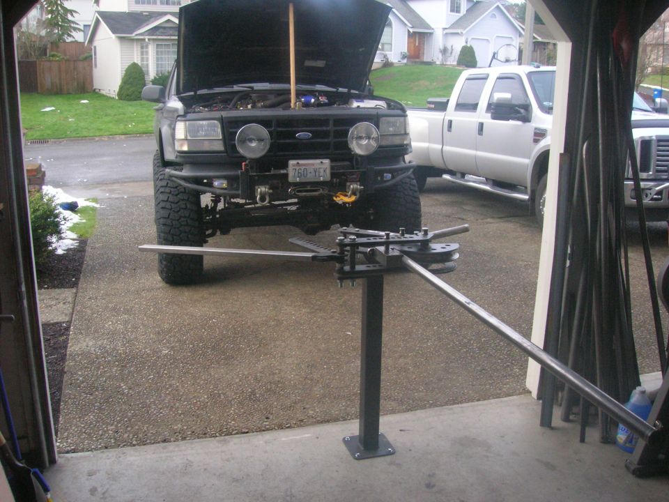 Black 1996 Ford Bronco with hood up and a pipe bender in front.