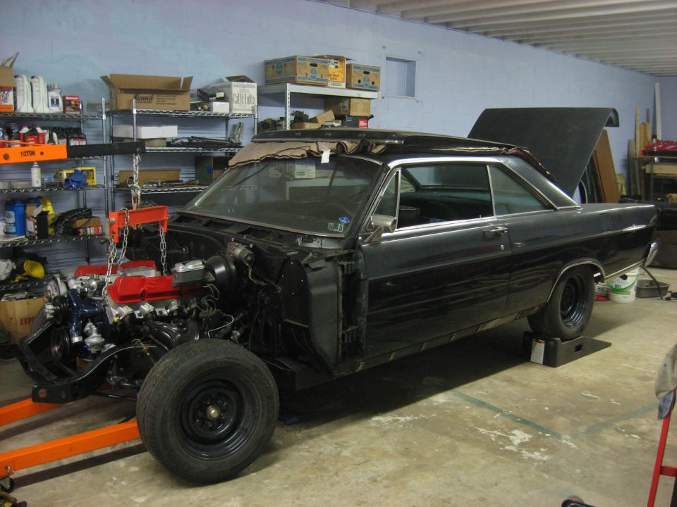 1965 Ford Galaxie coupe in a garage, engine being installed.