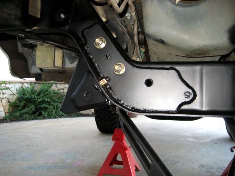 1996 Ford Bronco - A black steel bracket is bolted to the frame of a vehicle, which is supported by red jack stands. The vehicle appears to be a 1996 Ford Bro…