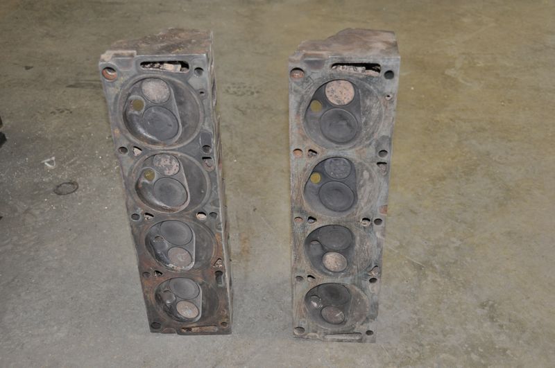 Two old engine cylinder heads sitting on a concrete floor