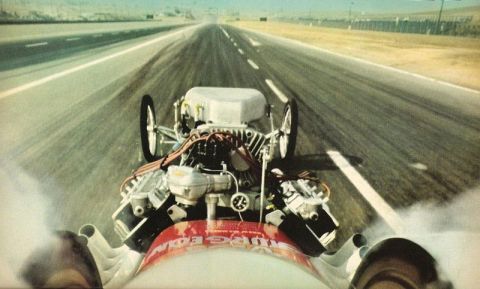 1974 Ford Ranchero - A dragster speeds down the track, its powerful engine in full view as smoke billows from the tires.