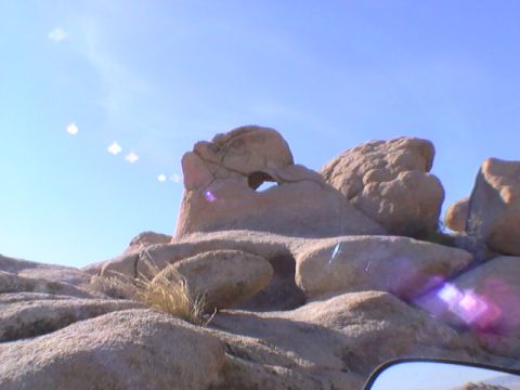 1997 Ford Ranger - A natural rock formation with a hole in the center is silhouetted against a clear blue sky. The foreground shows a rocky landscape with spa…