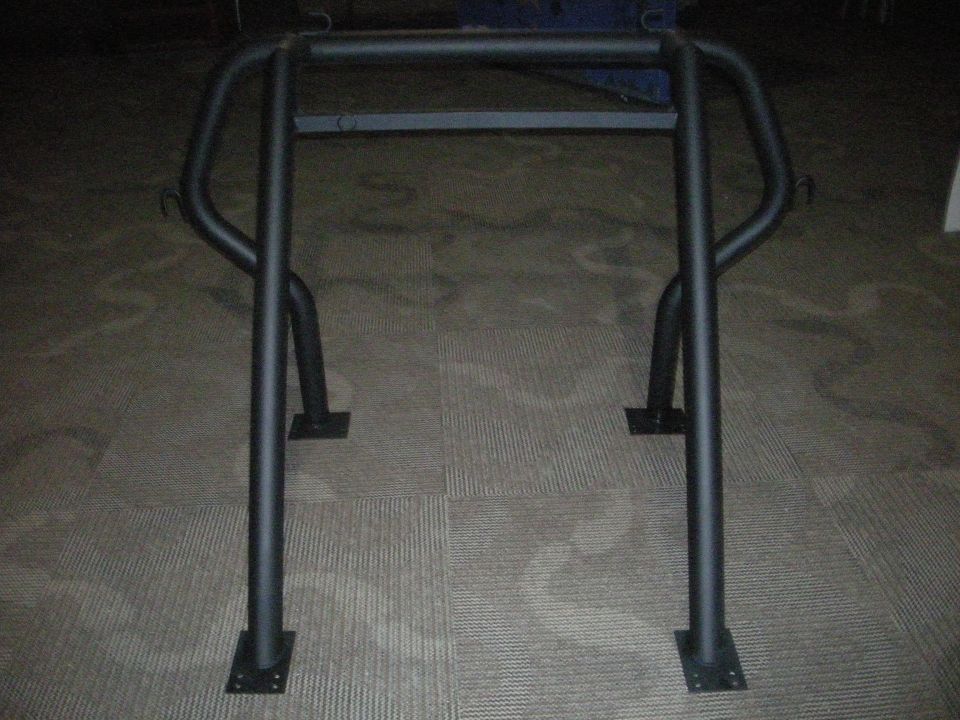 Black roll cage with four mounting plates on a carpeted floor.