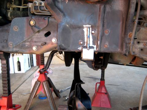 1996 Ford Bronco - Close-up of vehicle frame and suspension components supported by jack stands, showing a welded bracket.