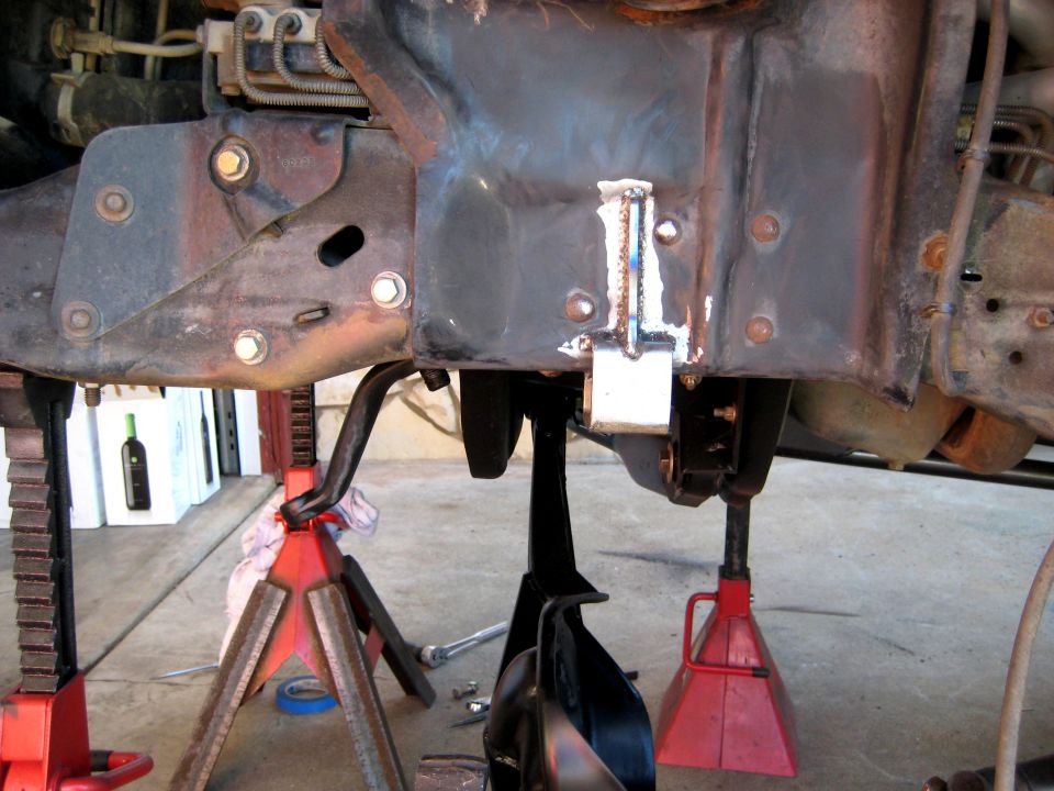 Vehicle frame and suspension parts on jack stands. Welded bracket on frame