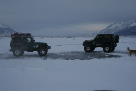 1990 Chevrolet Suburban - Two Jeeps navigate a snowy landscape with a dog nearby.
