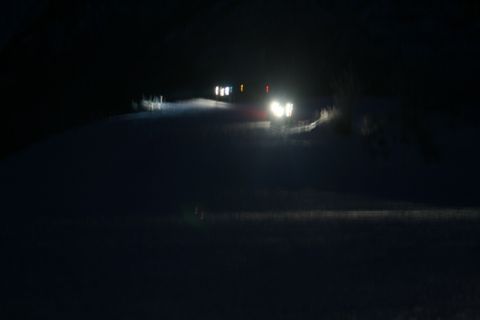 1990 Chevrolet Suburban - Vehicles navigate a snowy road in the dark, illuminated by their headlights.
