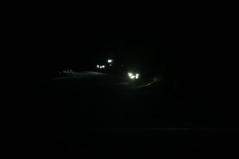 1990 Chevrolet Suburban - A vehicle's headlights illuminate the darkness on a road at night.