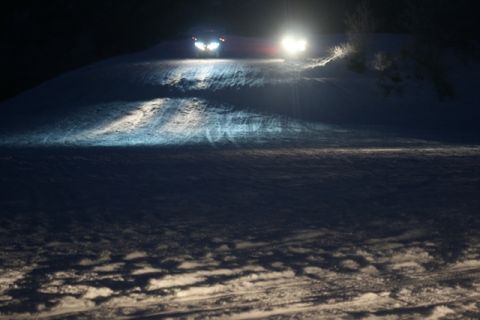 1990 Chevrolet Suburban - Headlights illuminate a snowy incline as two vehicles ascend the hill in the dark.