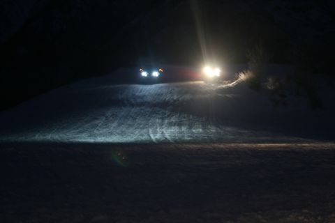 1990 Chevrolet Suburban - Headlights cut through the darkness as two vehicles ascend a snow-covered slope.