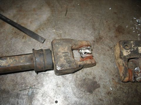 1978 Ford Bronco - Close-up of damaged steering linkage components on a metal surface, with a chisel in the background.