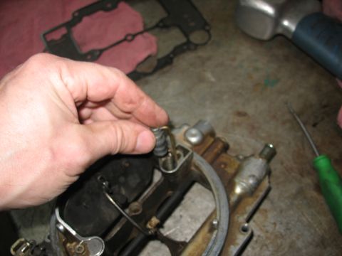 1978 Ford Bronco - Close-up of a hand working on a carburetor component, with tools and gaskets in the background.