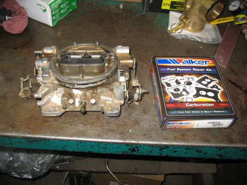 1978 Ford Bronco - Carburetor and its associated repair kit shown on a workbench.