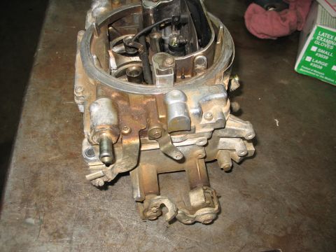 1978 Ford Bronco - A carburetor, likely from a classic vehicle, sits on a workbench. The part shows signs of age and use.