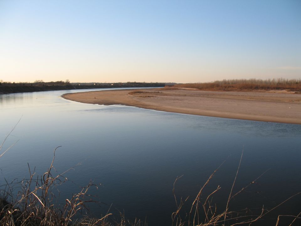 Calm river bending past a sandbar at dusk