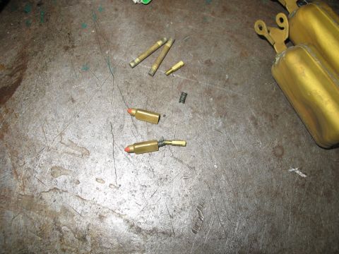 1978 Ford Bronco - Carburetor floats and jets laid out on a metal surface.