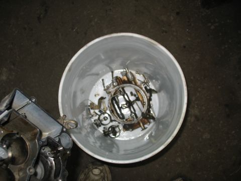 1978 Ford Bronco - A white bucket contains various disassembled carburetor components submerged in oil.