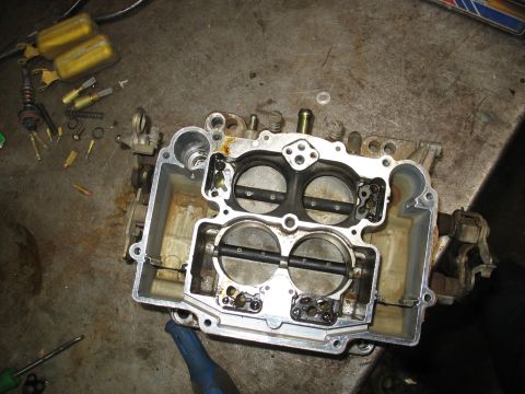 1978 Ford Bronco - A disassembled carburetor sits on a workbench, surrounded by its internal components and tools.