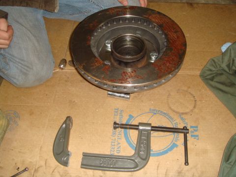 1992 Ford Bronco - A rusty brake rotor and hub assembly are shown with a C-clamp, likely for a repair or maintenance task.