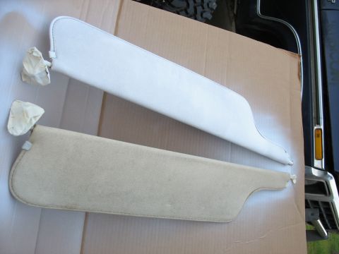 1978 Ford Bronco - Two car sun visors, one beige and one white, are laid out on cardboard for painting.