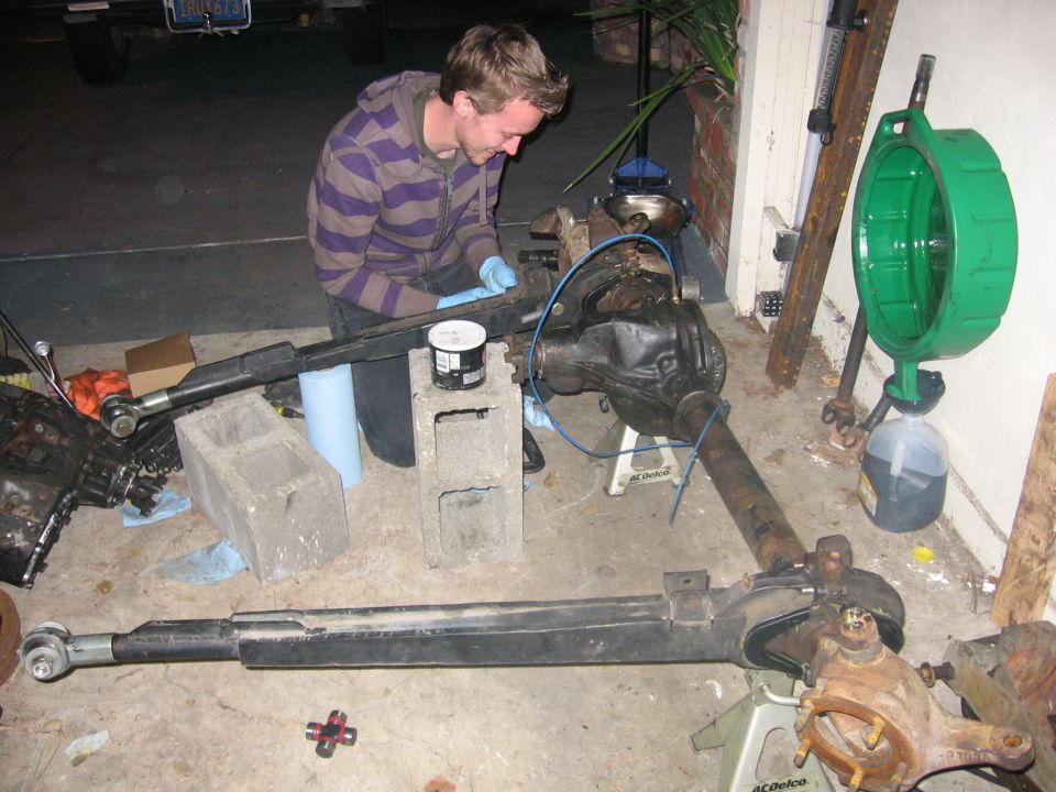 Man working on an axle and differential supported on cinder blocks