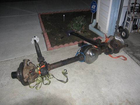 1989 Ford Bronco - Photograph of a complete solid front axle with knuckles and differential laid on a driveway.