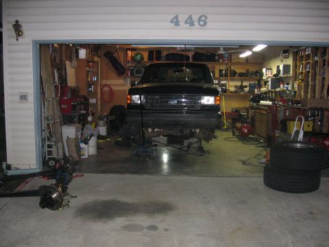 1989 Ford Bronco - Photograph of a black Ford truck raised on jack stands inside a garage with the number 446 on the door.