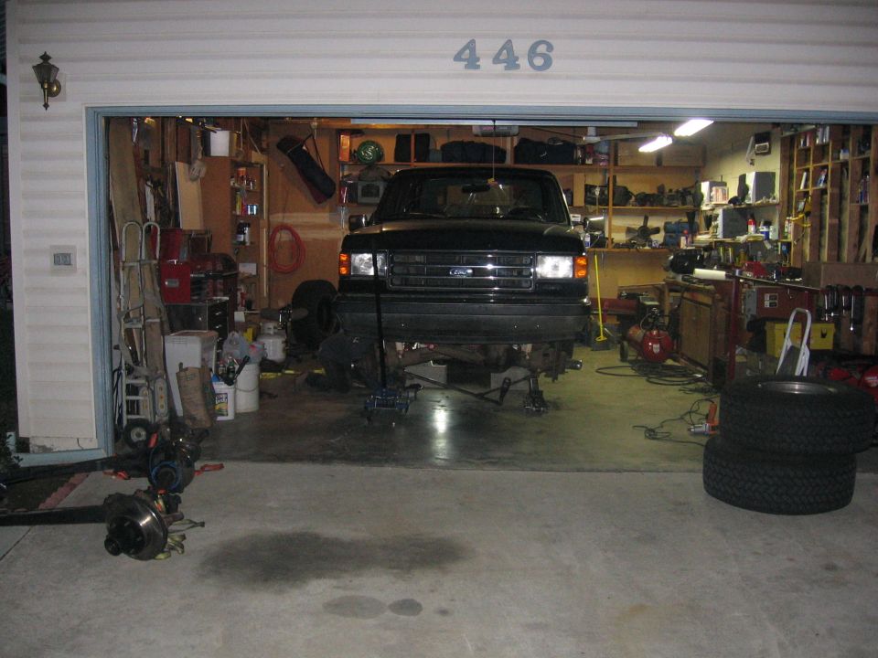 Black Ford truck on jack stands in an open garage marked 446
