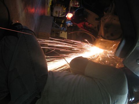 1989 Ford Bronco - Photo of someone grinding metal inside a vehicle with a shower of sparks, not a technical document.