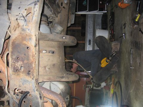 1989 Ford Bronco - Photo of a person working under a vehicle frame in a garage, not a technical document.