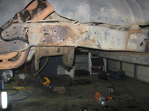 1989 Ford Bronco - Photo of a vehicle frame undercarriage with tools on the floor, not a technical document.