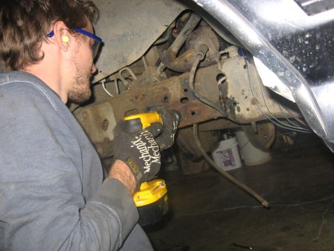 1989 Ford Bronco - Photo of a person using a power tool under a vehicle, not a technical document.